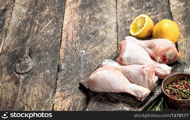 Raw chicken legs with spices and lemon. On wooden background.. Raw chicken legs with spices and lemon.