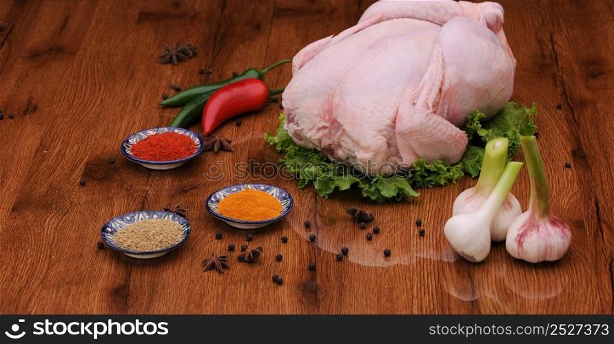 raw chicken meat with herbs and lettuce with garlic and pepper on the varnished board. raw meat on the board with spices