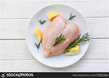 raw chicken meat with rosemary and lemon / fresh raw chicken breast heart shaped fillet on white plate , top view
