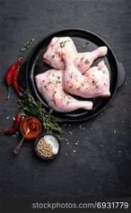 Raw chicken quarters, legs in a pan on a dark background. Top view.