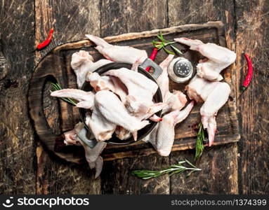 Raw chicken wings with garlic and herbs in a bowl . On wooden background.. Raw chicken wings with garlic and herbs in a bowl .