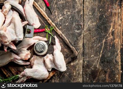 Raw chicken wings with garlic and herbs in a bowl . On wooden background.. Raw chicken wings with garlic and herbs in a bowl .