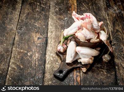 Raw chicken wings with garlic and herbs in a bowl . On wooden background.. Raw chicken wings with garlic and herbs in a bowl .