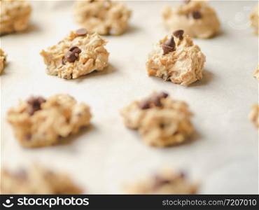 Raw chocolate chips cookie dough on wax paper in black baking tray.