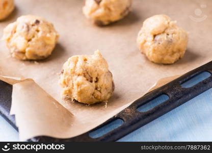 Raw cookie dough on a baking tray with parchment paper, selective focus