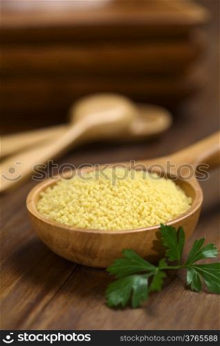 Raw couscous on wooden spoon with parsley leaf on the side (Very Shallow Depth of Field, Focus one third into the couscous)
