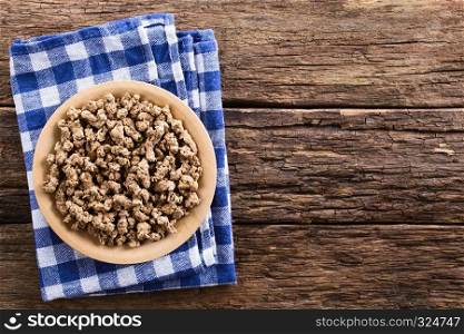 Raw dehydrated soy meat, soy protein, soya chunks or textured vegetable protein on wooden plate, photographed with copy space overhead on rustic wood. Raw Dehydrated Soy Meat