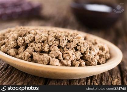Raw dehydrated soy meat, soy protein, soya chunks or textured vegetable protein on wooden plate, photographed on rustic wood (Selective Focus, Focus in the middle of the image). Raw Dehydrated Soy Meat