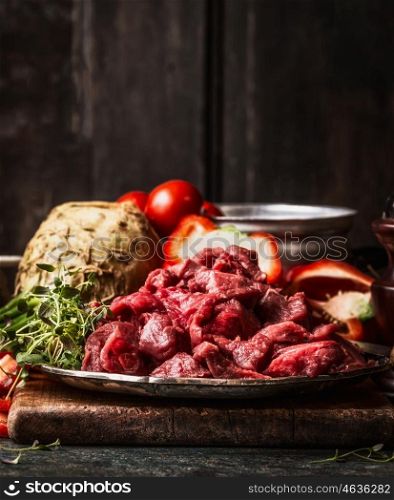 Raw diced beef meat and organic vegetables ingredient for Stew or goulash cooking. Food preparation on aged kitchen table at wooden background, top view