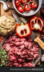 Raw diced beef meat , vegetables ingredient , kitchen knife and cooking pot . Stew or goulash preparation, top view