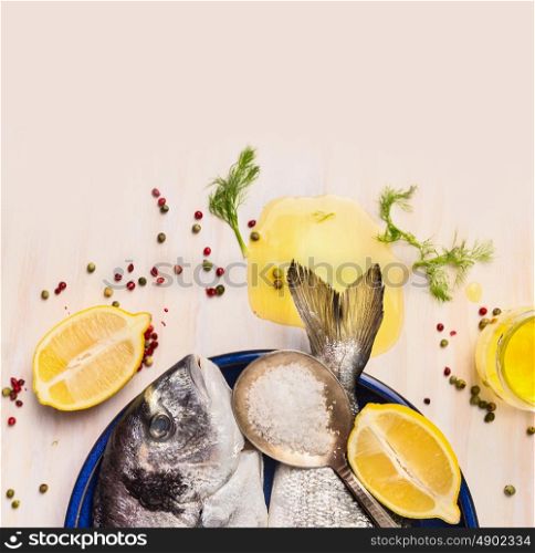 raw dorado fish with oil and lemon on white wooden background, top view, close up