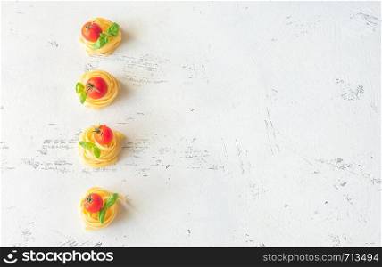 Raw fettuccine with cherry tomatoes and fresh basil leaves on the white background