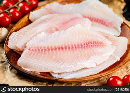 Raw fish fillet on a plate with a branch of tomatoes. Macro background. High quality photo. Raw fish fillet on a plate with a branch of tomatoes.