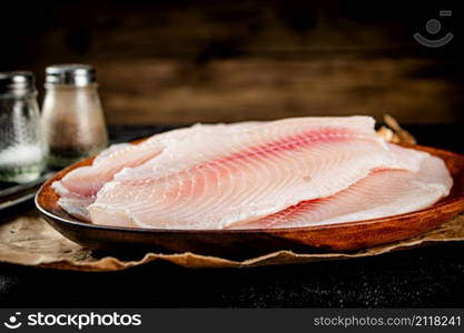 Raw fish fillet on a plate with spices. On a wooden background. High quality photo. Raw fish fillet on a plate with spices.