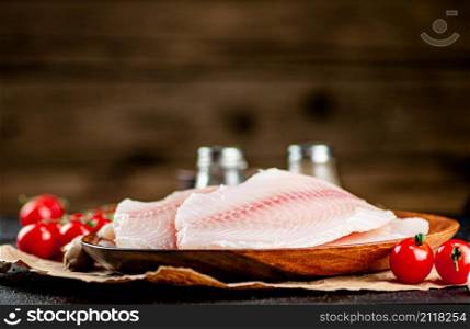 Raw fish fillet on a plate with spices. On a wooden background. High quality photo. Raw fish fillet on a plate with spices.