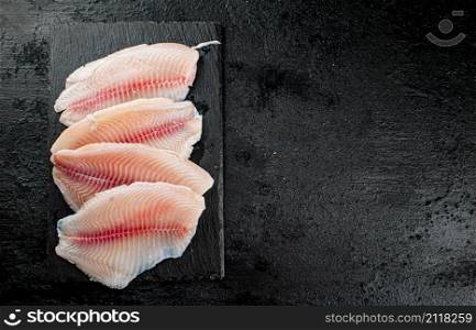 Raw fish fillet on a stone board. On a black background. High quality photo. Raw fish fillet on a stone board.