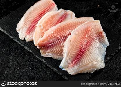Raw fish fillet on a stone board. On a black background. High quality photo. Raw fish fillet on a stone board.