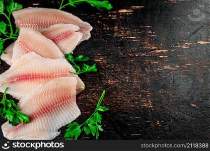 Raw fish fillet with parsley. On a rustic dark background. High quality photo. Raw fish fillet with parsley.
