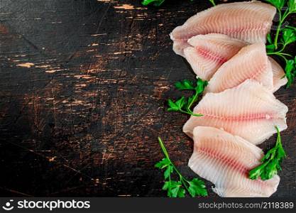 Raw fish fillet with parsley. On a rustic dark background. High quality photo. Raw fish fillet with parsley.