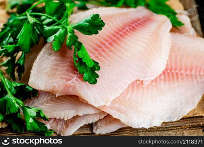 Raw fish fillet with parsley. On a wooden background. High quality photo. Raw fish fillet with parsley.