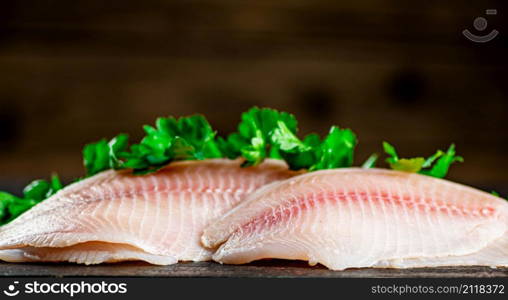 Raw fish fillet with parsley. On a wooden background. High quality photo. Raw fish fillet with parsley.