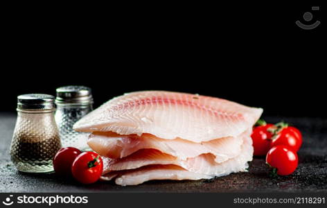 Raw fish fillet with tomatoes and spices. On a black background. High quality photo. Raw fish fillet with tomatoes and spices.