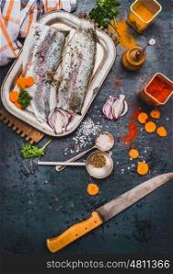 Raw fish fillets with kitchen knife , spices and cut vegetables, cooking preparation on dark rustic background, top view