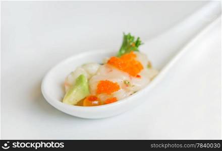 raw fish , red caviar and vegetables in white spoon