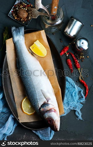 raw fish with lemon and aroma spice on a table