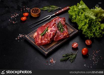 Raw flank beef steak and ingredients for cooking on a wooden board, close up. Raw organic marbled beef steaks with spices on a wooden cutting board