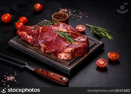 Raw flank beef steak and ingredients for cooking on a wooden board, close up. Raw organic marbled beef steaks with spices on a wooden cutting board