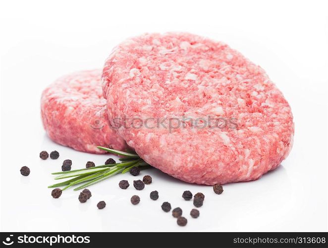 Raw fresh beef burgers with pepper and rosemarine on white background
