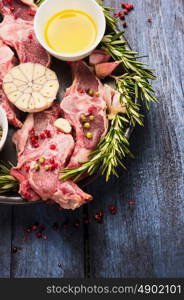 Raw fresh lamb with garlic, rosemary and oil, preparation on rustic wooden background