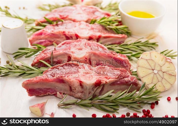 Raw fresh lamb with rosemary and garlic on white wooden background, close up