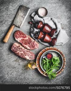 Raw fresh marbled meat Steak with meat cleaver seasonings on dark rustic concrete background, top view. Meat cooking preparation