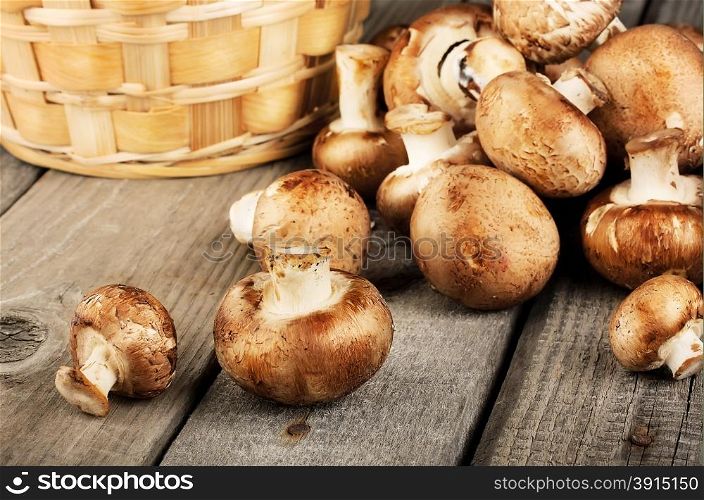 Raw fresh mushrooms with a basket on a wooden background