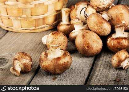 Raw fresh mushrooms with a basket on a wooden background