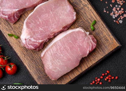 Raw fresh pork meat steak with salt, spices and herbs on a wooden cutting board