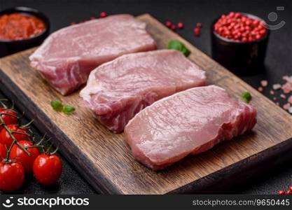 Raw fresh pork meat steak with salt, spices and herbs on a wooden cutting board