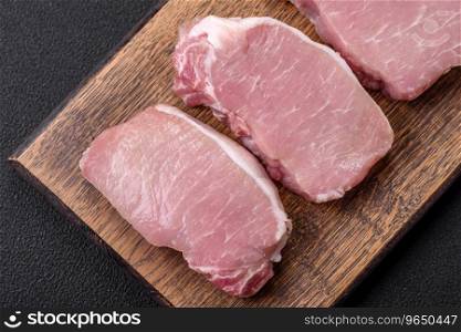 Raw fresh pork meat steak with salt, spices and herbs on a wooden cutting board
