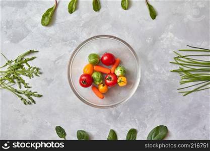 Raw fresh vegetables in a plate on a gray background, a stage of preparation of a salad, a photo from a series of step-by-step preparation of a salad. Healthy food. Top view, flat lay. Raw fresh vegetables in a plate