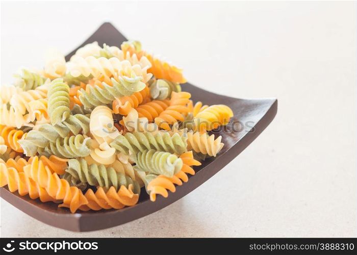 Raw fusilli pasta on wooden tray, stock photo