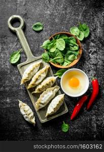 Raw gedza dumplings with chili pepper, egg and spinach. On dark rustic background. Raw gedza dumplings with chili pepper, egg and spinach.