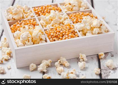 Raw golden sweet corn seeds and popcorn in white wooden box on light background