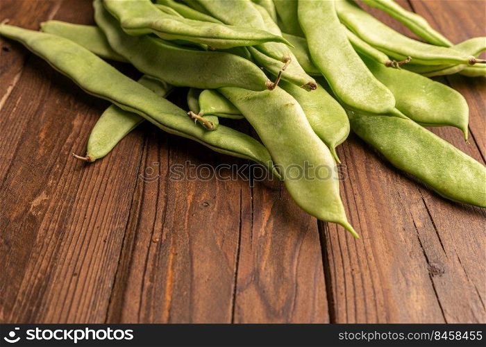 Raw green beans closeup. Fresh green bean also known as french beans, string beans, snap bean, snaps and haricots vert on wooden