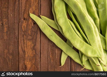 Raw green beans closeup. Fresh green bean also known as french beans, string beans, snap bean, snaps and haricots vert on wooden