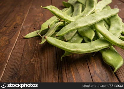 Raw green beans closeup. Fresh green bean also known as french beans, string beans, snap bean, snaps and haricots vert on wooden