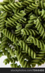 Raw green fusilli pasta, natural based on spinach and spirulina. Delicious and healthy food. Close-up. Raw green fusilli pasta, natural based on spinach and spirulina. Delicious and healthy food. Close-up.