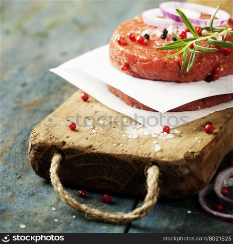 Raw Ground beef meat Burger steak cutlets with seasoning on vintage wooden boards