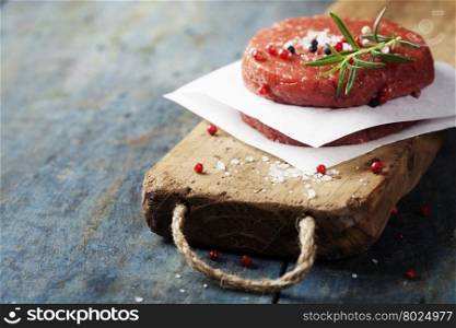 Raw Ground beef meat Burger steak cutlets with seasoning on vintage wooden boards